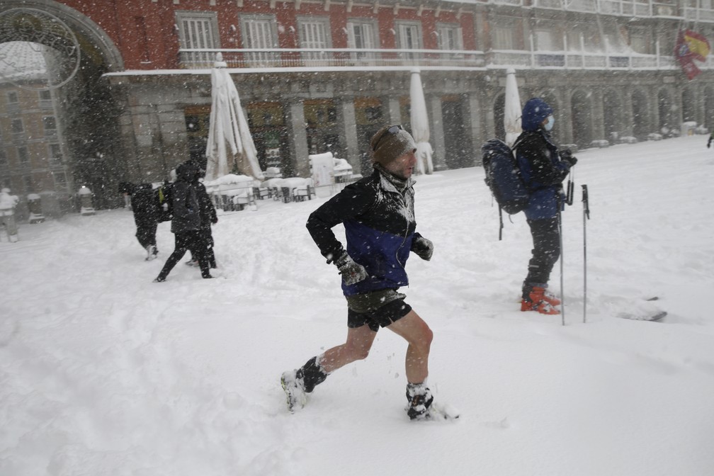 Um homem corre cruzando a Plaza Mayor durante uma forte nevasca em Madrid — Foto: Andrea Comas / AP Photo